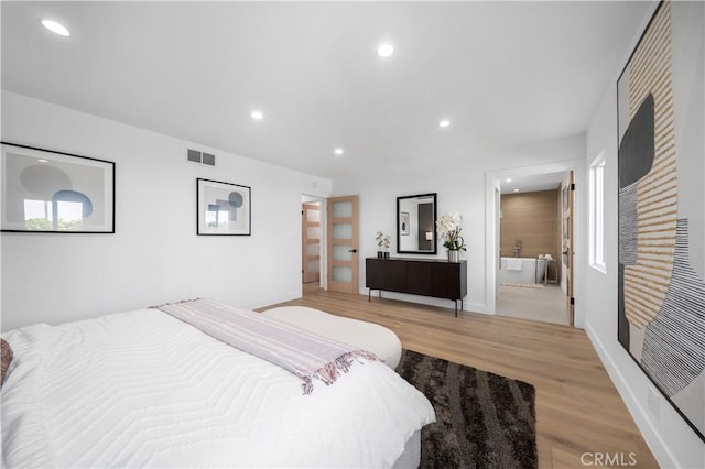 bedroom with connected bathroom and light hardwood / wood-style flooring