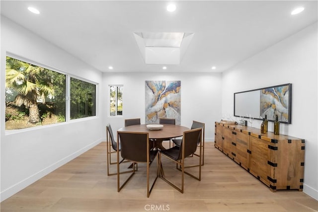 dining area with a skylight and light hardwood / wood-style floors