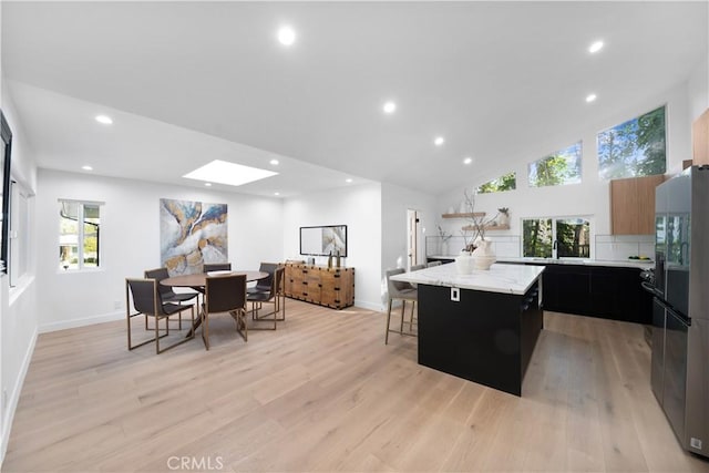 kitchen featuring a breakfast bar area, stainless steel fridge, a kitchen island, and light hardwood / wood-style flooring