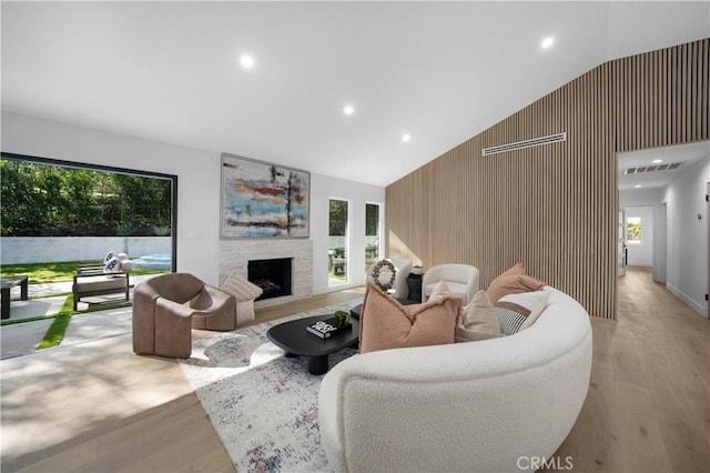 living room featuring high vaulted ceiling, light hardwood / wood-style floors, and wood walls