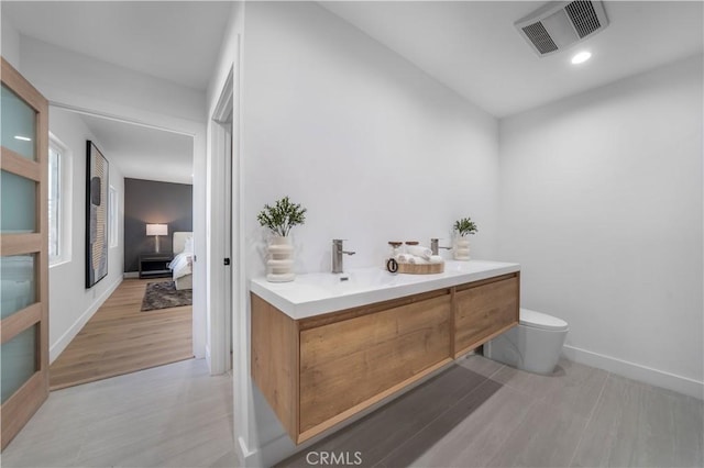 bathroom featuring vanity, hardwood / wood-style flooring, and toilet