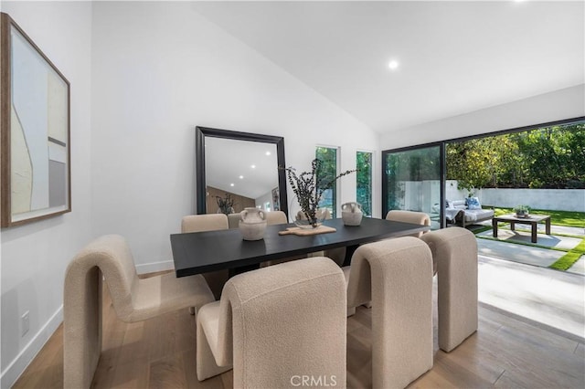 dining area with high vaulted ceiling and light hardwood / wood-style floors