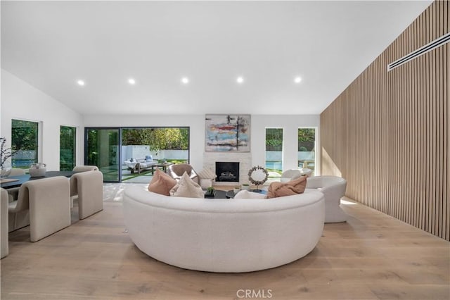 living room with a wealth of natural light, high vaulted ceiling, and light wood-type flooring