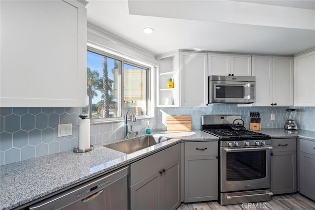 kitchen featuring gray cabinets, sink, backsplash, stainless steel appliances, and light stone countertops