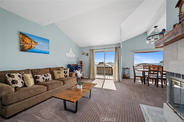 living room with a tiled fireplace, lofted ceiling, carpet flooring, and a notable chandelier