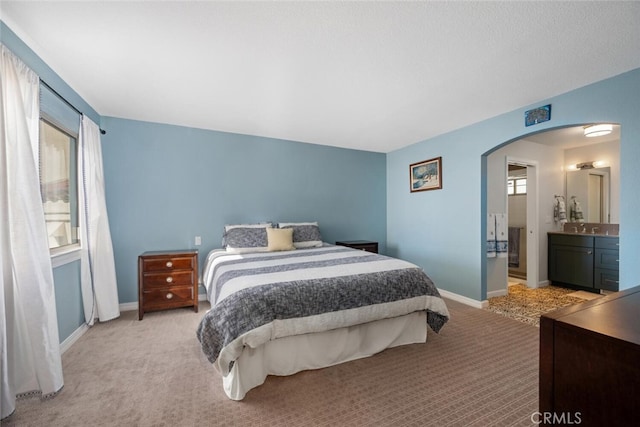 bedroom with light carpet, sink, and connected bathroom