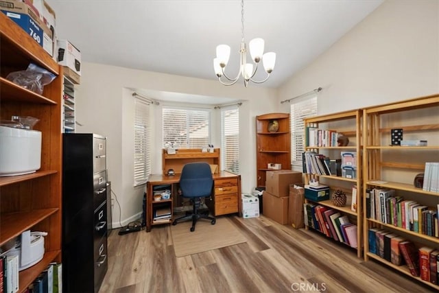 home office featuring vaulted ceiling, hardwood / wood-style floors, and an inviting chandelier