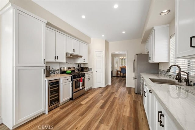 kitchen with wine cooler, white cabinets, sink, and stainless steel gas range oven