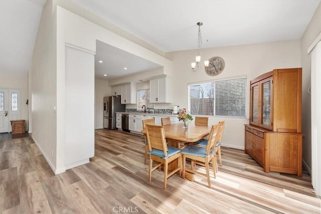 dining space featuring a notable chandelier, light hardwood / wood-style floors, sink, and a healthy amount of sunlight