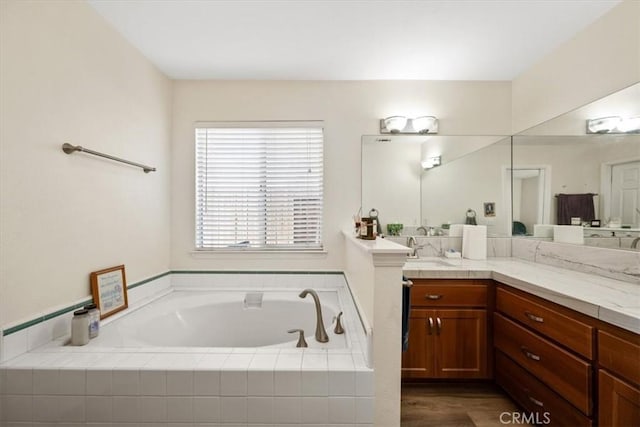 bathroom featuring vanity and tiled bath