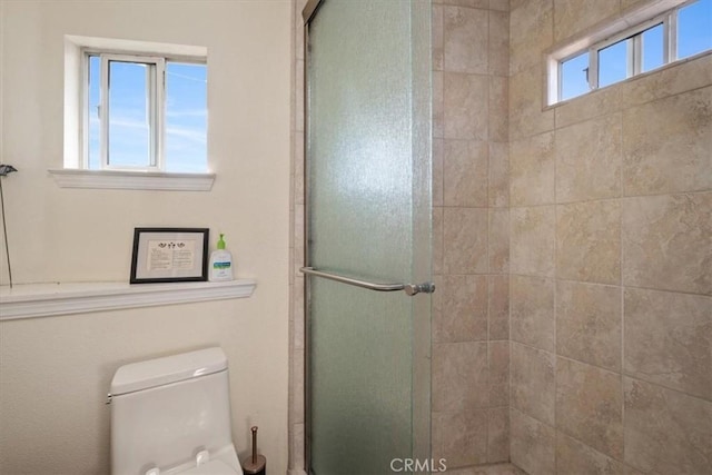 bathroom featuring a shower with shower door and toilet