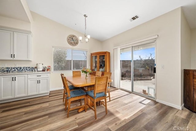 dining room featuring vaulted ceiling, wood-type flooring, and a chandelier