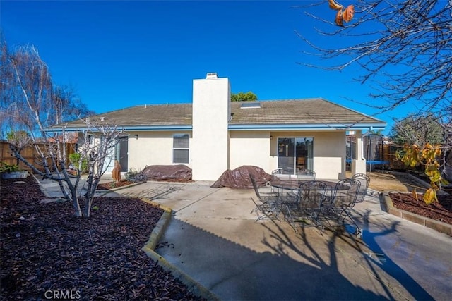 back of property with a trampoline and a patio