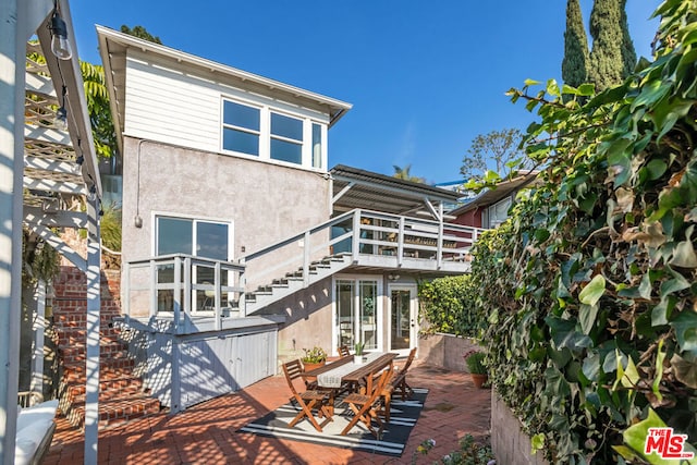 back of house with a balcony, a hot tub, and a patio