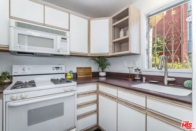 kitchen with white appliances, sink, and white cabinets