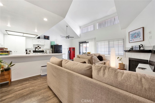 living room with hardwood / wood-style floors, high vaulted ceiling, and ceiling fan