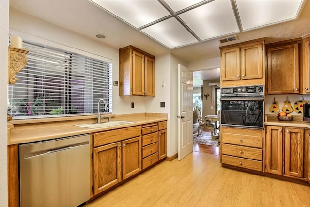 kitchen with light hardwood / wood-style flooring, sink, black oven, and dishwasher