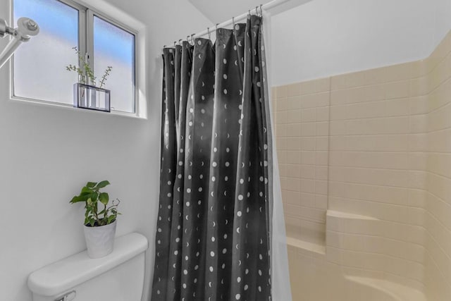 bathroom with shower / bathtub combination with curtain and toilet