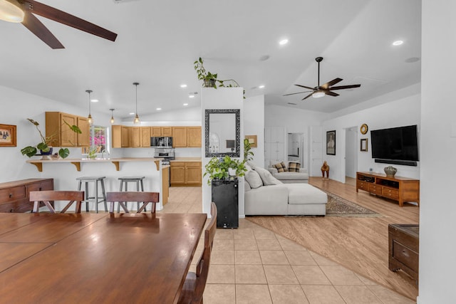 living room featuring ceiling fan, lofted ceiling, and light tile patterned floors