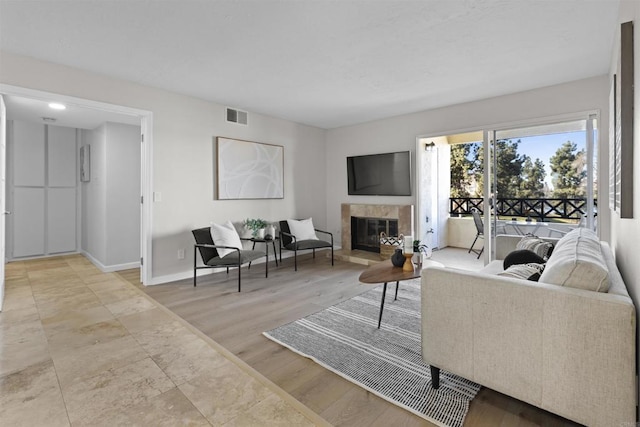 living room with a tiled fireplace and light hardwood / wood-style floors