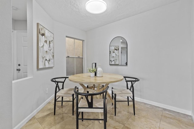 dining space with light tile patterned floors and a textured ceiling