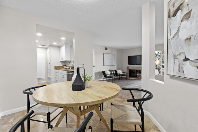 dining space with sink, a fireplace, and a textured ceiling