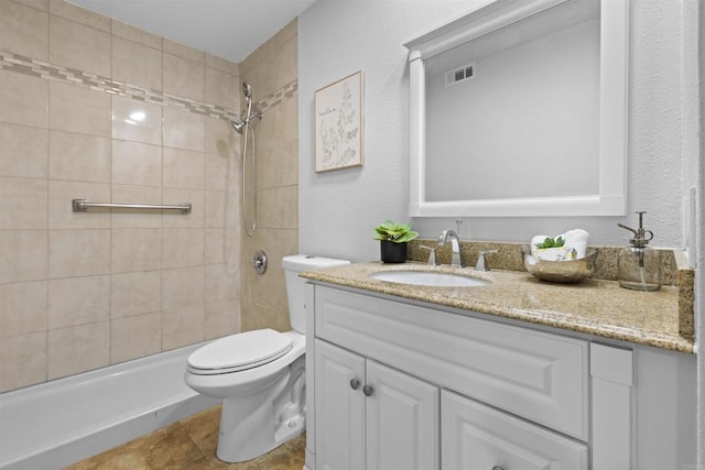 full bathroom with toilet, visible vents, a tile shower, and vanity