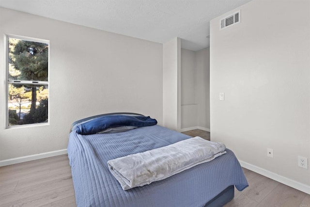 bedroom with baseboards, visible vents, and light wood finished floors