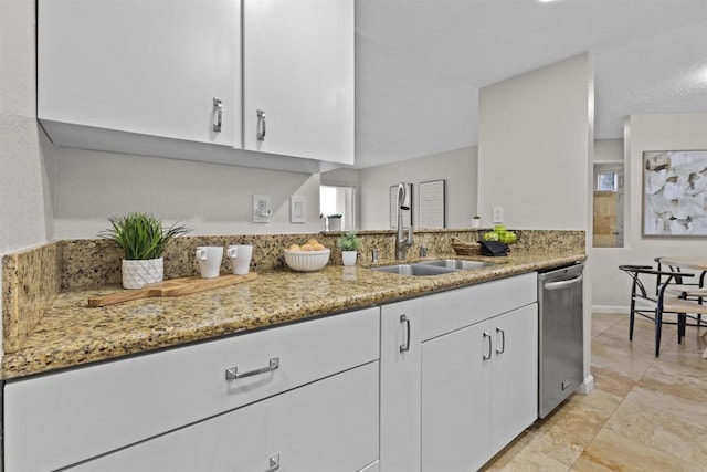 kitchen featuring light stone counters, stainless steel dishwasher, white cabinetry, a sink, and baseboards