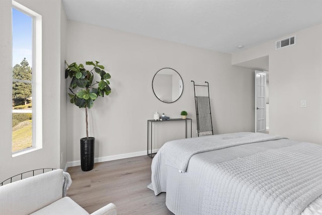 bedroom with light wood finished floors, multiple windows, visible vents, and baseboards