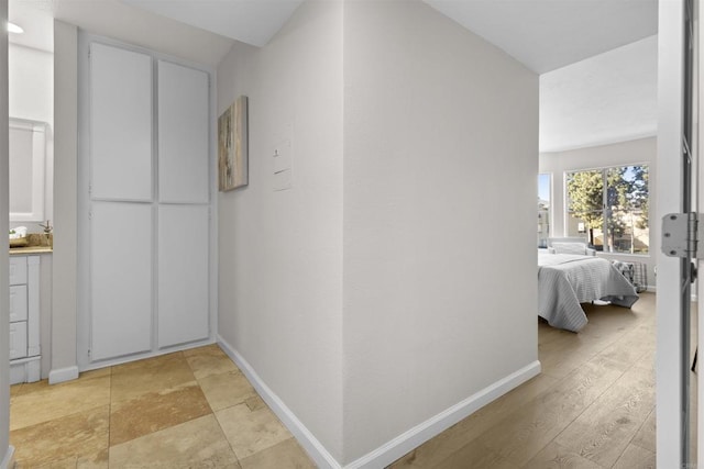 corridor with light wood-type flooring and baseboards