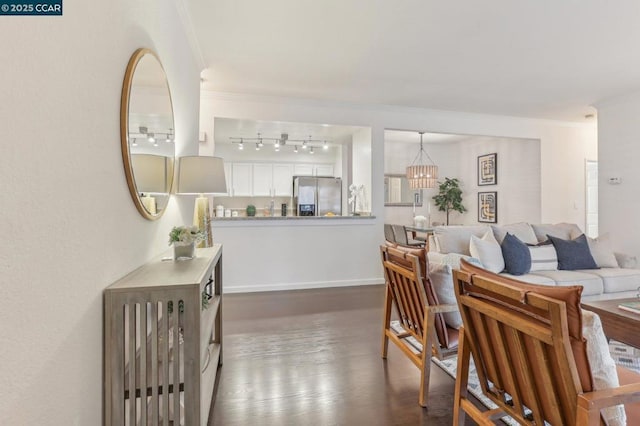 living room featuring crown molding, rail lighting, dark hardwood / wood-style floors, and an inviting chandelier