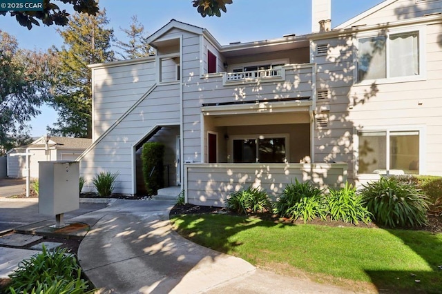 townhome / multi-family property featuring a balcony and a front lawn