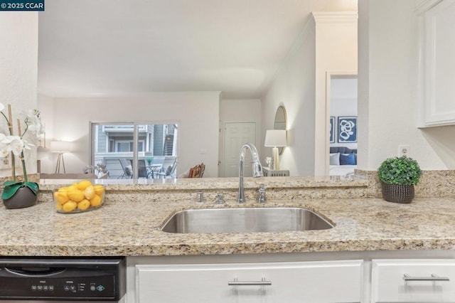 kitchen featuring dishwashing machine, sink, light stone countertops, and white cabinets