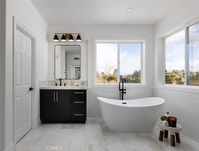 bathroom featuring tile walls, vanity, and a washtub