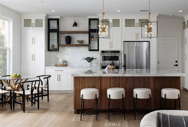 kitchen with appliances with stainless steel finishes, a kitchen island with sink, and decorative light fixtures