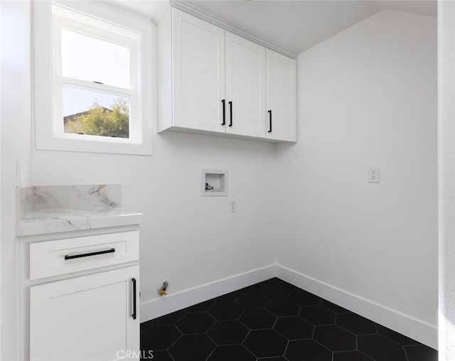 clothes washing area featuring cabinets, dark tile patterned floors, and hookup for a washing machine