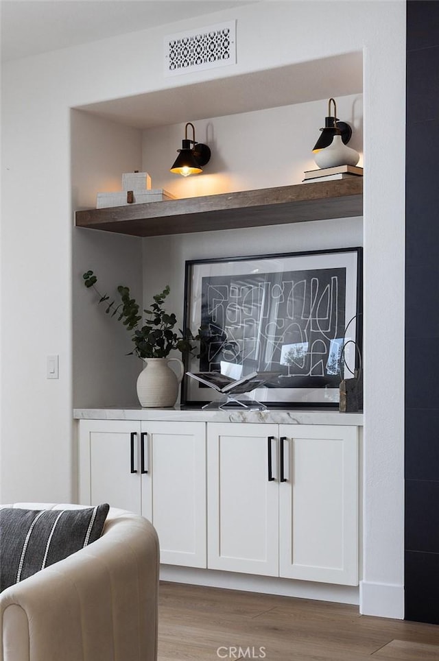 bar featuring white cabinets and light hardwood / wood-style floors