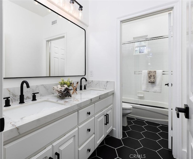 full bathroom with tile patterned floors, toilet, vanity, and shower / bath combination with glass door