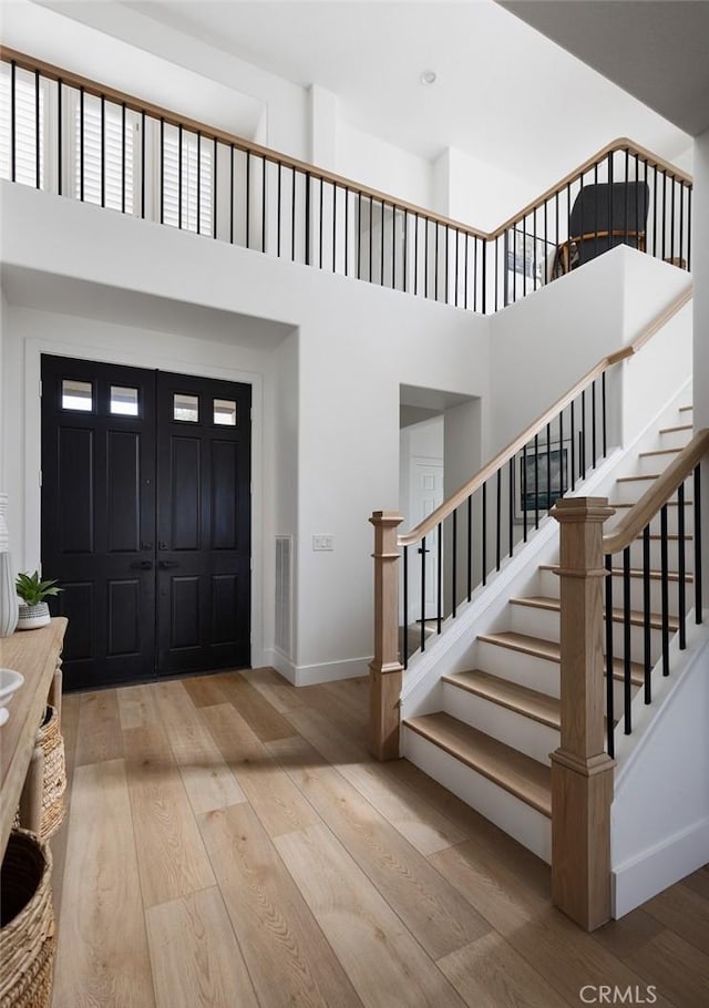 foyer entrance featuring a towering ceiling and wood-type flooring