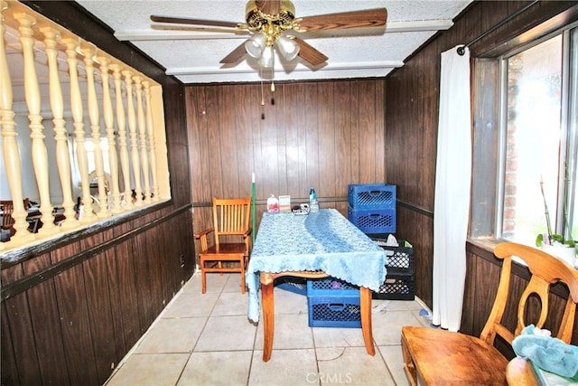 dining room with a textured ceiling, beamed ceiling, light tile patterned flooring, and wooden walls