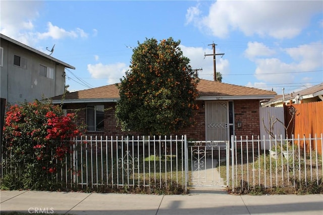 view of front of house featuring a fenced front yard, roof with shingles, and brick siding