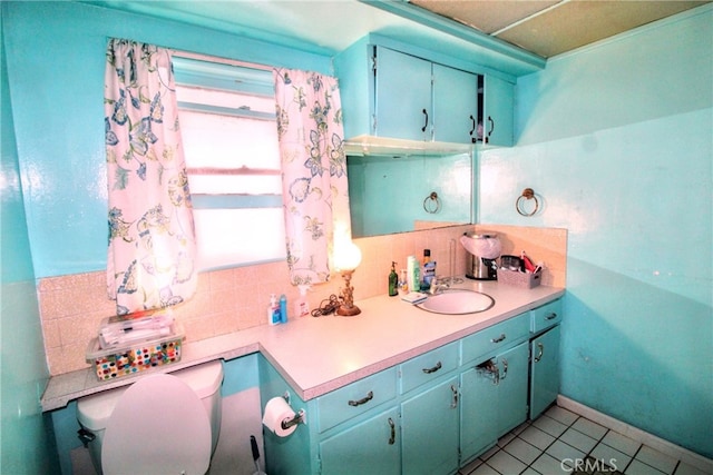 bathroom with toilet, decorative backsplash, vanity, tile patterned flooring, and baseboards