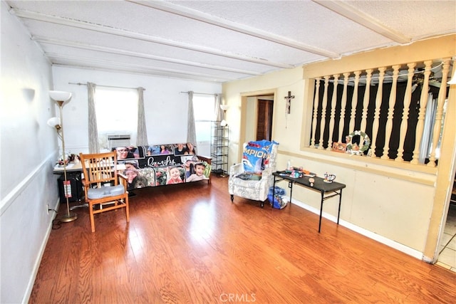 interior space featuring beamed ceiling, baseboards, and wood finished floors