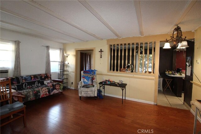 living room with wood-type flooring, a chandelier, and beamed ceiling