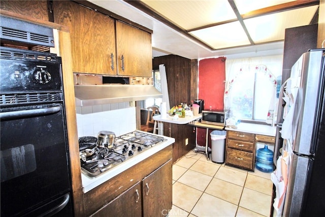 kitchen featuring appliances with stainless steel finishes, light countertops, light tile patterned flooring, and decorative backsplash