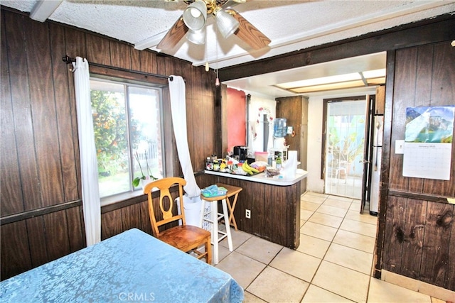 kitchen featuring light tile patterned flooring, wooden walls, a textured ceiling, and fridge