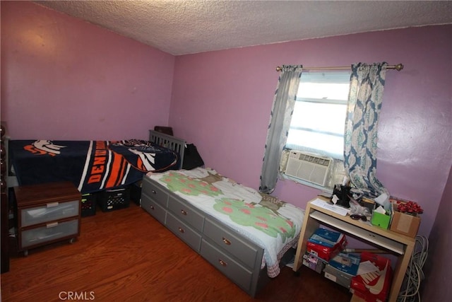 bedroom with cooling unit, a textured ceiling, and wood finished floors