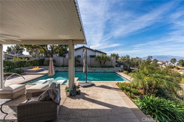 view of swimming pool featuring ceiling fan, a mountain view, and a patio area