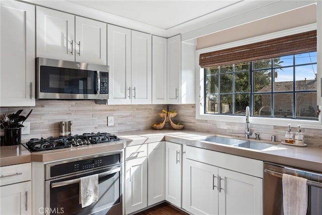 kitchen with stainless steel appliances, sink, white cabinets, and decorative backsplash